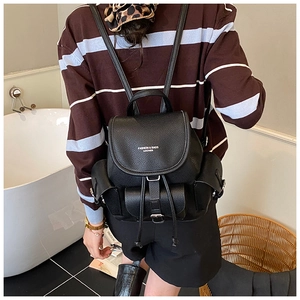 Detail of black pebbled leather backpack featuring drawstring closure and magnetic flap