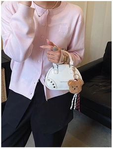 Close-up of white mini bowling bag with silver studs and cute brown teddy bear charm