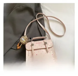 Pink polka dot handbag with a cute plush doll and metal twist lock on gray fabric