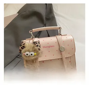 Detail of pink polka dot square handbag with plush monster charm and top handle