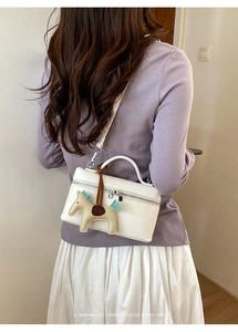 Vue arrière d'un sac à main blanc en cuir grainé avec breloque cheval et fermeture éclair