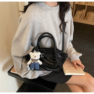 Close-up of black ruched PU leather handbag featuring a cute plush bear charm accessory