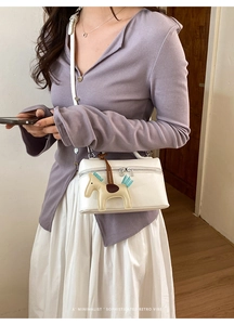 Détail du sac à main blanc en cuir grainé avec breloque poney bleue et zip argenté brillant
