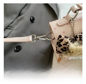 Detail of pink polka dot bag featuring silver metal clasp and leopard bow charm