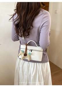 Sac bandoulière blanc à motif litchi avec breloque cheval sur une tenue de mannequin