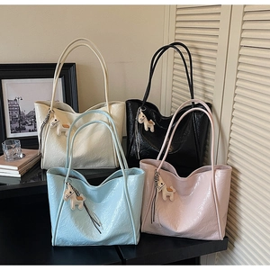 Detailed display of four wrinkled leather tote bags in cream, black, blue and pink with charms
