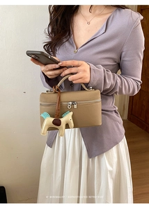Détail du sac à main en cuir grainé avec double fermeture éclair et breloque cheval