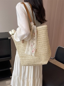 Large beige woven bucket tote bag with brown leather straps and floral lace scarf detail