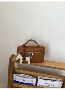 Gros plan d'un sac à main en cuir marron caramel avec un charmant pendentif cheval