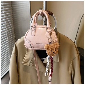 Pink mini bowling bag with silver studs and a cute brown bear charm on trench coat