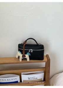 Détail d'un sac à main en cuir noir avec fermetures éclair et pendentif de cheval