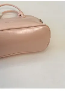 Detail view of the reinforced wide bottom and leather texture on the light pink shell bag