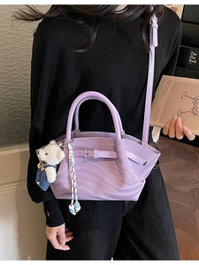 Fashionable purple PU leather handbag with bear pendant shown on model in cozy interior