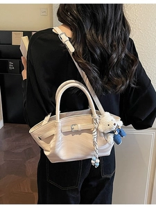 Chic beige leather handbag with teddy bear charm and adjustable shoulder strap