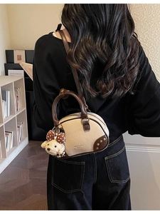 Cream and brown faux leather pillow bag with cute bear charm shown on a model