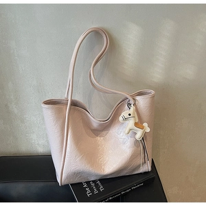 Detailed close-up of light pink tote bag with pleated texture and pony charm accessory