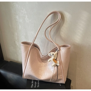 Detail of light pink tote bag with pleated leather texture and a white horse charm