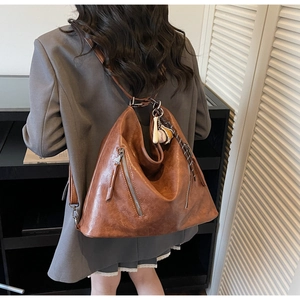 Details des braunen Lederrucksacks im Vintage-Stil mit Reißverschlüssen und Anhänger