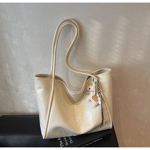 Close-up detail of cream tote bag featuring retro wrinkled texture and horse charm