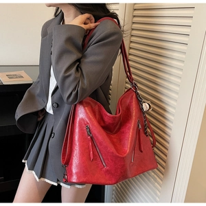 Detailansicht einer großen roten PU-Ledertasche mit einem kreativen Baseball-Anhänger