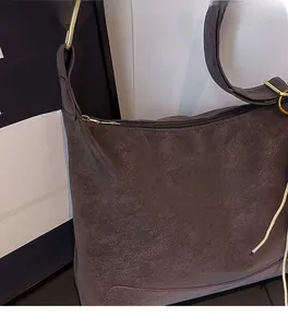 Close-up of brown PU leather texture with lychee grain and gold metal hardware on bag