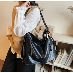 Detailansicht der schwarzen Kunstledertasche mit Reißverschluss und Baseball-Anhänger