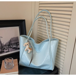 Detail of light blue tote bag with crinkle texture and white pony leather charm accessory