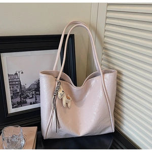 Detail of pink pleated leather tote bag with a small horse charm in a stylish setting