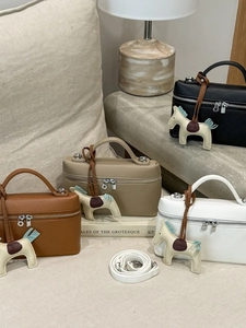 Sac à main élégant motif lychee avec breloque cheval en quatre couleurs sur un canapé
