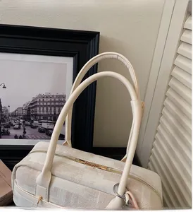 Close-up of beige woven texture handbag featuring gold hardware and long handles