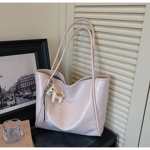 Close-up of light pink tote bag with crinkle texture and a white horse charm detail