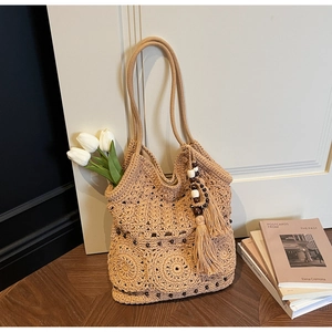 Dettaglio della borsa tote in maglia beige con ciondolo a nappa e perline in legno