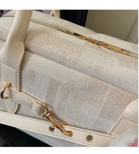 Detail view of cream tote bag featuring textured jacquard fabric and gold hardware