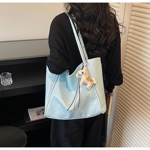 Detail of light blue tote bag with glossy pleated texture and a small horse charm