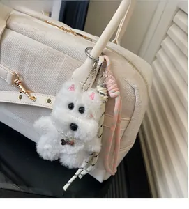 Detail of white plush puppy keychain with pearl necklace on a canvas tote bag