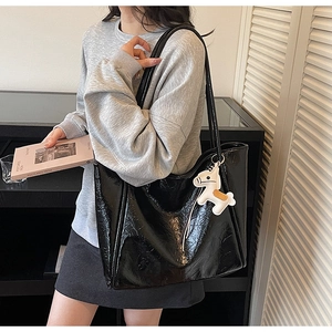 Detail of a large black tote bag with glossy crinkled texture and white horse charm