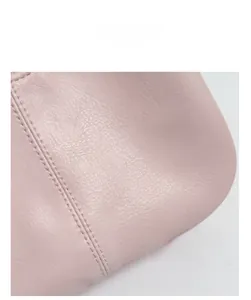 Détail macro du cuir rose avec double couture précise sur le sac à main pour femme