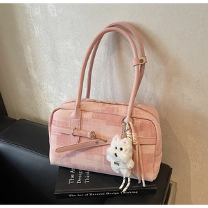 Pink checkered PU handbag with cute plush puppy charm on a black leather sofa