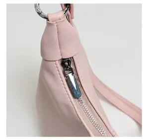 Gros plan détaillé sur la fermeture éclair argentée et l'anneau en D du sac en cuir rose