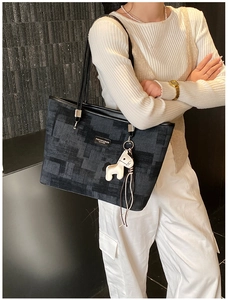 Detailed view of grey tote bag with pony charm and metallic logo on model's shoulder