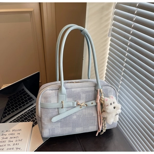 Detail of light blue tote bag with metallic buckles and a cute white puppy plush charm
