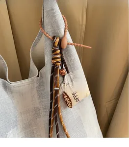 Detail of woven rope charm and mini canvas coffee cup pendant on a large shoulder bag