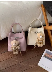 Close-up of litchi grain leather bucket bags with metal buckle and teddy bear charm