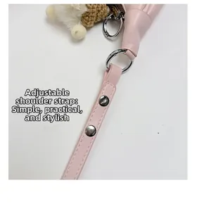 Détail de la bandoulière réglable en cuir rose avec rivets et charm au crochet