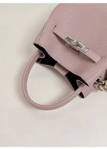 Detail of pink lychee leather handbag featuring wide handle and silver metallic clasp