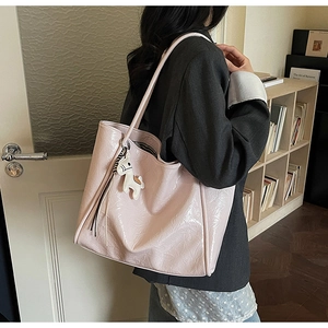 Detail of light pink oil wax leather tote bag with white horse charm and striped lining
