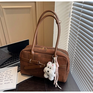 Detailed view of brown textured tote bag with cute plush puppy charm on a desk