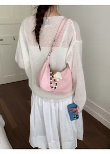 Vue détaillée du sac demi-lune rose avec breloques festives sur tricot blanc