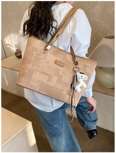 Detail of khaki tote bag with geometric pattern, leather patch and horse pendant
