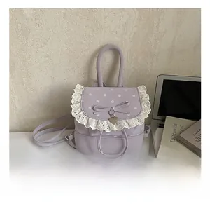 Détail du sac à dos lilas à pois avec dentelle blanche, nœud et pendentif en cœur